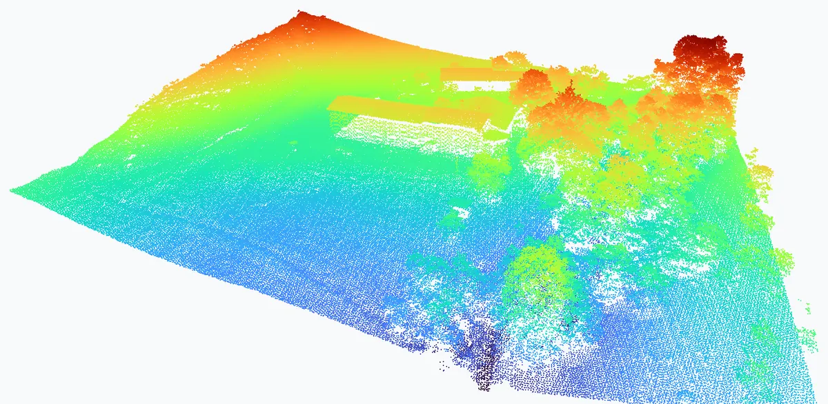 Nuage de points LiDAR aérien d'une ferme et de son bosquet, colorié par altitude : le terrain en bleu et vert, les toitures et la cime des arbres en orange et rouge